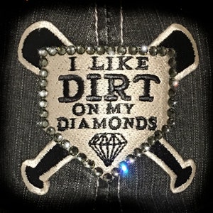 May include: A white patch with black embroidery that reads "I like dirt on my diamonds" with a diamond shape in the center. The patch is surrounded by a circle of black rhinestones and is sewn onto a black denim background with two white embroidered baseball bats.