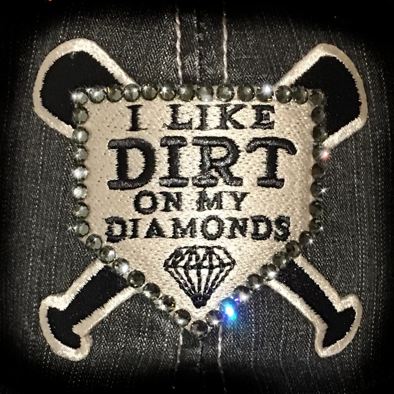 May include: A white patch with black embroidery that reads "I like dirt on my diamonds" with a diamond shape in the center. The patch is surrounded by a circle of black rhinestones and is sewn onto a black denim background with two white embroidered baseball bats.