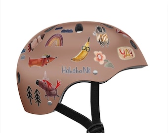 May include: A brown bicycle helmet with a variety of colorful stickers, including a banana, a bee, a dachshund, a unicorn, and the text "Hahaha, Nö".
