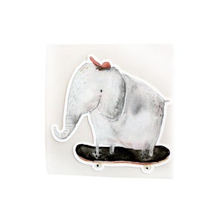 Könnte beinhalten: Ein grauer Elefant mit einer roten Schleife auf dem Kopf fährt auf einem schwarzen Skateboard mit weißen Rollen.