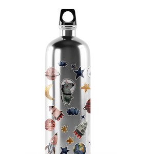 May include: A silver water bottle with a black lid and a variety of colorful space-themed stickers, including planets, stars, rockets, and a cartoon astronaut dog.