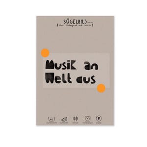 Peut inclure: Un transfert thermocollant beige avec le texte allemand "Musik an Welt aus" en lettres noires grasses. Le motif comprend deux cercles orange et plusieurs petites icônes. Le haut du transfert indique "BÜGELBILD" en noir.