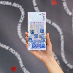 May include: A blue and white Ukrainian 50 hryvnia banknote featuring the Ukrainian trident and the words "ЄДНІСТЬ - СИЛА!" (Unity is Strength!)