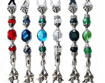 Puede incluir: Seis collares de plata con dijes y cuentas de cristal de diferentes colores. Las cuentas son rojas, azules, verdes y transparentes. Los dijes son ornamentados y tienen un diseño floral.