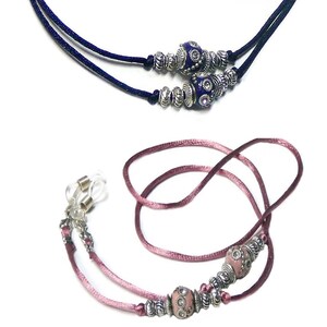 Puede incluir: Dos pares de cadenas para gafas con cuentas decorativas. Un par es azul marino con cuentas plateadas y azules. El otro par es rosa con cuentas plateadas y rosas.