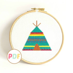 May include: A cross-stitch pattern of a colorful teepee with a brown base and a green, yellow, orange, and red patterned design. The pattern is displayed in a wooden embroidery hoop.