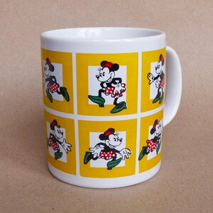 May include: White ceramic mug with a yellow background and multiple images of Minnie Mouse in different poses. Each image is framed in a yellow square.