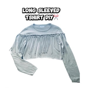 May include: A light blue long-sleeved t-shirt with fringe detailing across the chest. The shirt has a crew neck and a cropped hemline. Text at the top reads "LONG SLEEVED TSHIRT DIY".