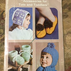 May include: Vintage Patons knitting pattern book titled "Accessories for Tots and Toddlers." The cover shows knitted baby items: a bonnet, slippers, booties, and a hat with a scarf. The book is labeled "Beehive Book No. 402."