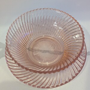 May include: A set of two pink glass bowls. The bowls have a spiral design and a scalloped edge. The bowls are made of a clear pink glass.