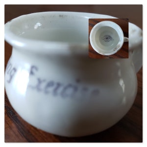 May include: White ceramic chamber pot with a blue and white eye design on the inside. The pot has the words "Morning Exercise" written on the side.