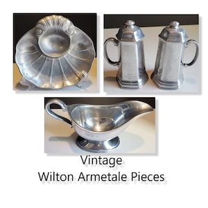 Puede incluir: Piezas vintage Wilton Armetale, que incluyen un pequeño plato en forma de concha, una salsera y dos saleros y pimenteros. Las piezas están hechas de peltre y tienen un acabado brillante plateado.