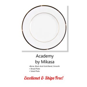 May include: A white plate with a black and gold rim. The plate has a gold inner band. The text "Academy by Mikasa" is below the plate. The plate is a bread plate and salad plate.
