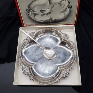 May include: A silver party set with a four-section serving dish and a matching spoon. The dish is decorated with a floral design and the text "Two Piece Party Set".