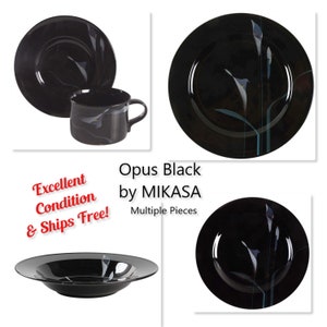 Könnte beinhalten: Schwarzes Mikasa Opus Black Geschirrset. Das Set beinhaltet Teller, eine Schüssel und eine Tasse. Die schwarzen Teile weisen ein Blumendesign mit weißen und türkisfarbenen Akzenten auf. Der Text "Opus Black by MIKASA" ist sichtbar.