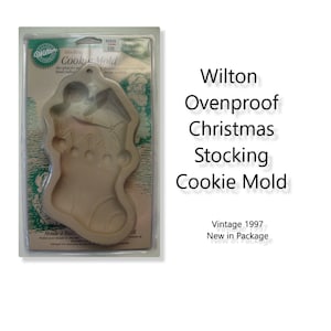 Puede incluir: Un molde para galletas de Navidad vintage Wilton a prueba de horno en forma de calcetín de Navidad. El molde está hecho de cerámica beige y presenta un diseño detallado de un calcetín de Navidad con una campana y adornos.
