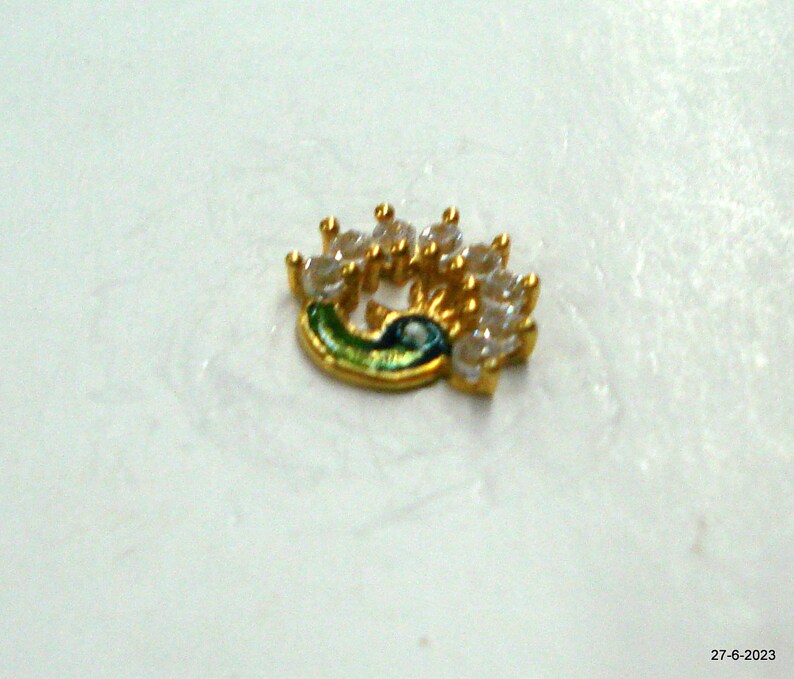 May include: Gold-toned nose ring shaped like a peacock with clear rhinestones.