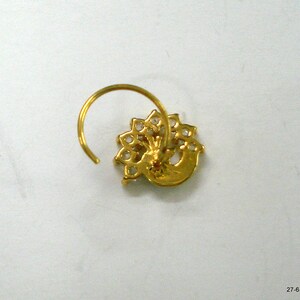 May include: A gold nose ring featuring a peacock design. The peacock is crafted from clear stones and has a gold body.