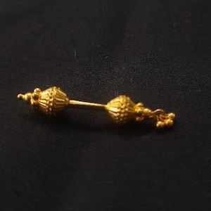 May include: A gold-colored nose ring with two decorative balls on either end.