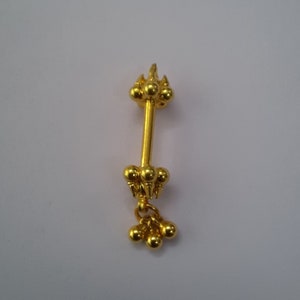 Op de afbeelding: Een gouden neusring met een hangende hanger. De hanger is gemaakt van drie kleine gouden balletjes.