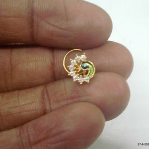 May include: Gold nose ring with a peacock design and white stones.