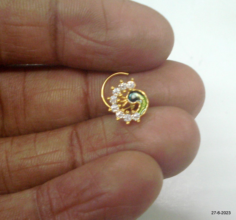May include: Gold nose ring with a peacock design and white stones.
