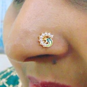 May include: A gold nose ring with a peacock design and white rhinestones.
