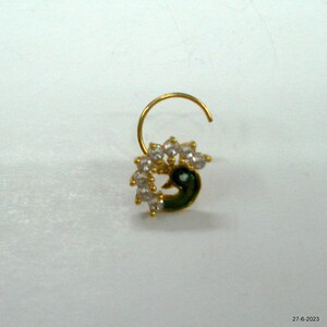 May include: A gold nose ring featuring a peacock design. The peacock is green and blue with white rhinestones.