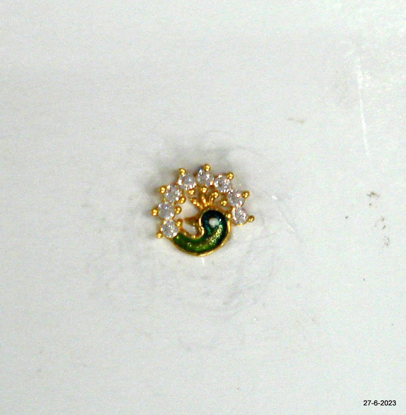 May include: A gold nose ring featuring a peacock design with white cubic zirconia stones.