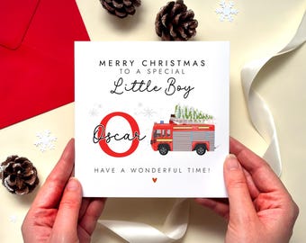 May include: A square white Christmas greeting card featuring the text Merry Christmas to a special little boy, the name Oscar in black script next to a large red letter O, and a red fire engine carrying a Christmas tree, ending with Have a wonderful time.