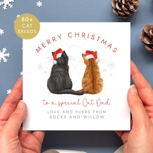 Könnte beinhalten: Eine quadratische Weihnachtsgrußkarte mit einem schwarzen und einem orangefarbenen getigerten Katzenpaar, die nebeneinander sitzen und rote Weihnachtsmützen tragen. Der Text lautet Merry Christmas to a special Cat Dad, Love and purrs from Socks and Willow.