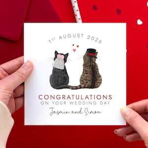 May include: A square white wedding greeting card featuring an illustration of two cats sitting side by side. One black cat wears a pink floral veil, and one brown tabby cat wears a black top hat. Text reads 1ST AUGUST 2026, CONGRATULATIONS ON YOUR WEDDING DAY, and Jasmin and Simon.