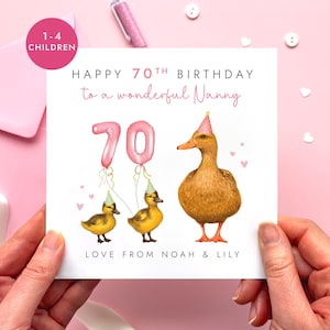 Könnte beinhalten: Eine quadratische Grußkarte mit dem Text Happy 70th Birthday to a wonderful Nanny. Das Design zeigt eine große braune Ente und zwei gelbe Entenküken mit Partyhüten, rosa Luftballonzahlen 70 sowie den Text Love from Noah & Lily.