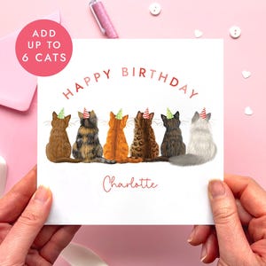 May include: A birthday card featuring six cats wearing party hats. The words "Happy Birthday" are arched across the top, with the name "Charlotte" below. A pink circle in the upper left corner reads "Add up to 6 Cats".
