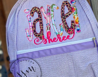 May include: Purple and white striped backpack with a personalized name "Jaycee Sheree" in colorful letters with animal print and floral accents.