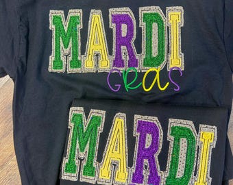 May include: Black t-shirt with a green, purple, and yellow glitter design that says "Mardi Gras".