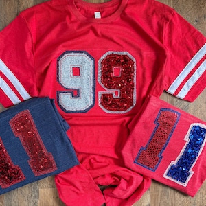 Doppelt gestapeltes Nummern-T-Shirt mit gestreiften Ärmeln- unisex- glitzernd