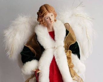 May include: A red velvet angel figurine with white faux fur trim and gold accents. The angel has a white feather halo and holds a red tassel.