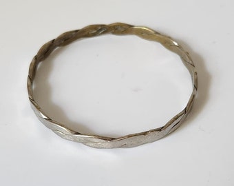 May include: A silver braided bangle bracelet.