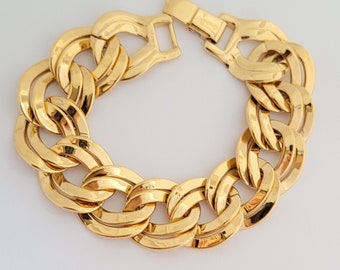 May include: A gold-toned chain link bracelet with a large, chunky design. The bracelet is made of metal and has a polished finish.