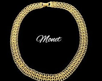 May include: A gold-toned chain necklace with a woven design. The necklace is labeled "Monet".