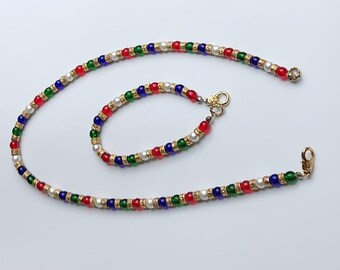 May include: A set of gold-toned beaded jewelry with red, green, blue, and white beads. The set includes a necklace and a bracelet.