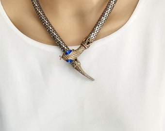 May include: A silver snake-shaped choker necklace with a blue jeweled snake head pendant.