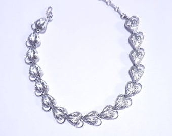 May include: A silver necklace with a chain and a series of heart-shaped pendants. Each pendant is decorated with a textured design.