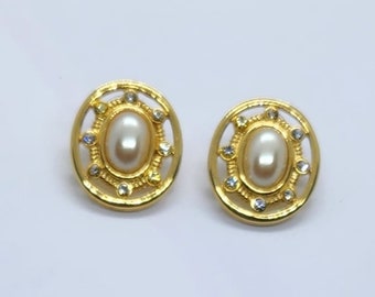 May include: A pair of gold-tone earrings with a white pearl center and clear rhinestone accents.