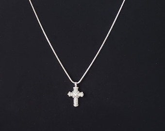 May include: A silver chain necklace with a small, sparkly cross pendant.