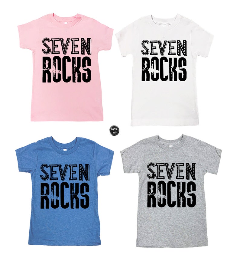 Puede incluir: Cuatro camisetas de diferentes colores con el texto "SEVEN ROCKS" impreso en negro en la parte delantera. Las camisetas son rosa, blanca, azul y gris.