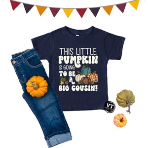May include: A navy blue t-shirt with a graphic of pumpkins and the text "This Little Pumpkin is Going to Be a Big Cousin!"
