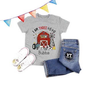 Peut inclure: T-shirt gris avec une grange rouge, des animaux de la ferme et le texte "I AM THREE-I-E-1-0" et "Bubba".