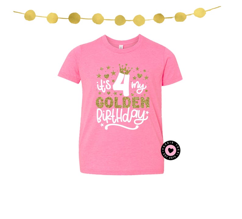 May include: Pink t-shirt with the text "It's my 4 Golden Birthday" in gold glitter and white script. The design includes a gold crown and stars. A gold garland hangs above the shirt.